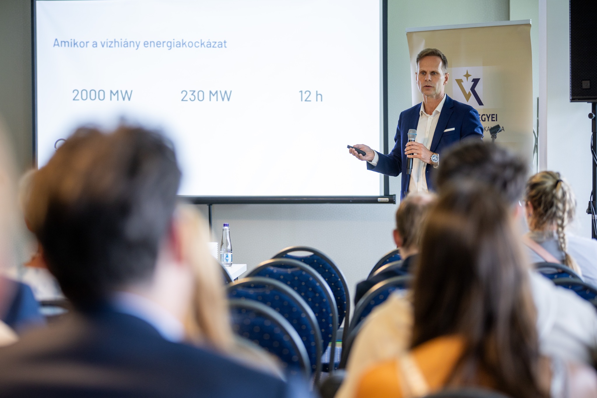Drávecz Kont Szilárd közönség előtt beszél a vízhiány energetikai kockázatairól, vetített előadás mellett.